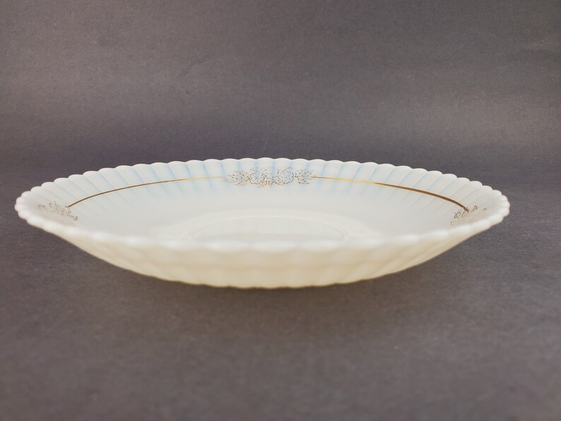 May include: A white, scalloped-edge saucer with a gold rim and a delicate floral design in gold.