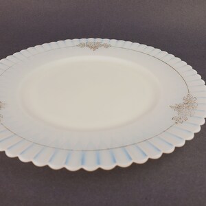 May include: A white glass plate with a scalloped edge and a blue and gold floral design.
