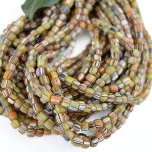 Peut inclure: Gros plan sur un brin de perles de verre colorées. Les perles sont petites et rondes, avec une variété de couleurs et de motifs. Les perles sont enfilées sur un fil transparent.