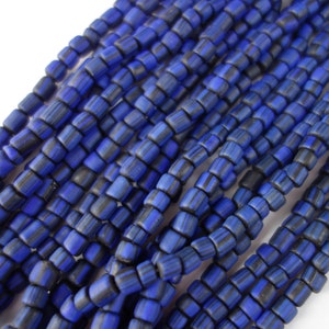 Könnte beinhalten: Eine Strähne aus blauen und schwarzen Glasperlen. Die Perlen sind quadratisch und haben ein gestreiftes Muster.