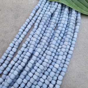 Könnte beinhalten: Eine Strähne hellblauer quadratischer Perlen. Die Perlen sind aus Holz und haben eine matte Oberfläche.