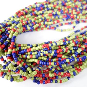 Könnte beinhalten: Eine lange Perlenkette in Grün, Rot und Blau. Die Perlen sind klein und gleichmäßig groß, wodurch ein strukturiertes und optisch ansprechendes Muster entsteht.