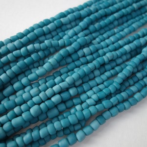 May include: A strand of turquoise blue glass beads. The beads are small and uniform in size and shape, creating a smooth and consistent look.