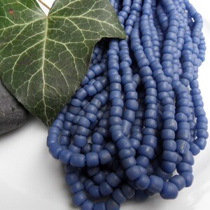 Könnte beinhalten: Eine Strähne blauer Glasperlen. Die Perlen sind klein und rund und liegen in einem lockeren Haufen. Die Perlen sind hellblau und haben eine matte Oberfläche.