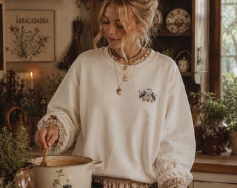 Sudadera acogedora con cuervo y escudo inspirada en la magia práctica y con temática de brujas.