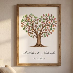 May include: A framed print featuring a tree with a heart-shaped canopy of leaves in green, orange, and red. The tree's trunk and branches are brown. The names "Matthias & Natascha" and a date are printed below the tree.