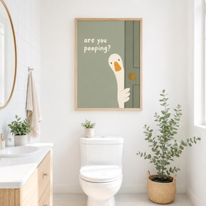 May include: A framed art print featuring a cartoon goose peeking from behind a green door. The text "are you pooping?" is above the goose. The artwork is in a bathroom setting, with a toilet and plants.