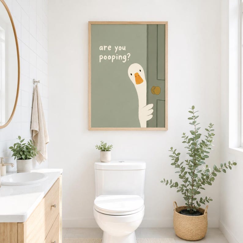 May include: A framed art print featuring a cartoon goose peeking from behind a green door. The text "are you pooping?" is above the goose. The artwork is in a bathroom setting, with a toilet and plants.