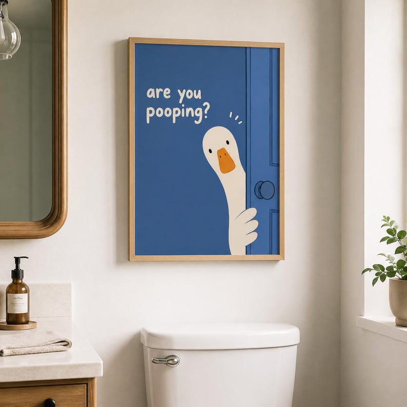 May include: A framed print featuring a cartoon goose peeking from behind a blue door. The text "are you pooping?" is displayed in white. The artwork is in a bathroom setting, above a white toilet.
