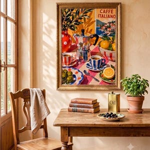 Puede incluir: Una lámina de arte enmarcada titulada CAFFÈ ITALIANO que representa una cafetera moka plateada, dos tazas de café con rayas rojas y azules, un cuenco de naranjas, un plato de aceitunas verdes y un jarrón con ramas de olivo sobre un mantel a cuadros.
