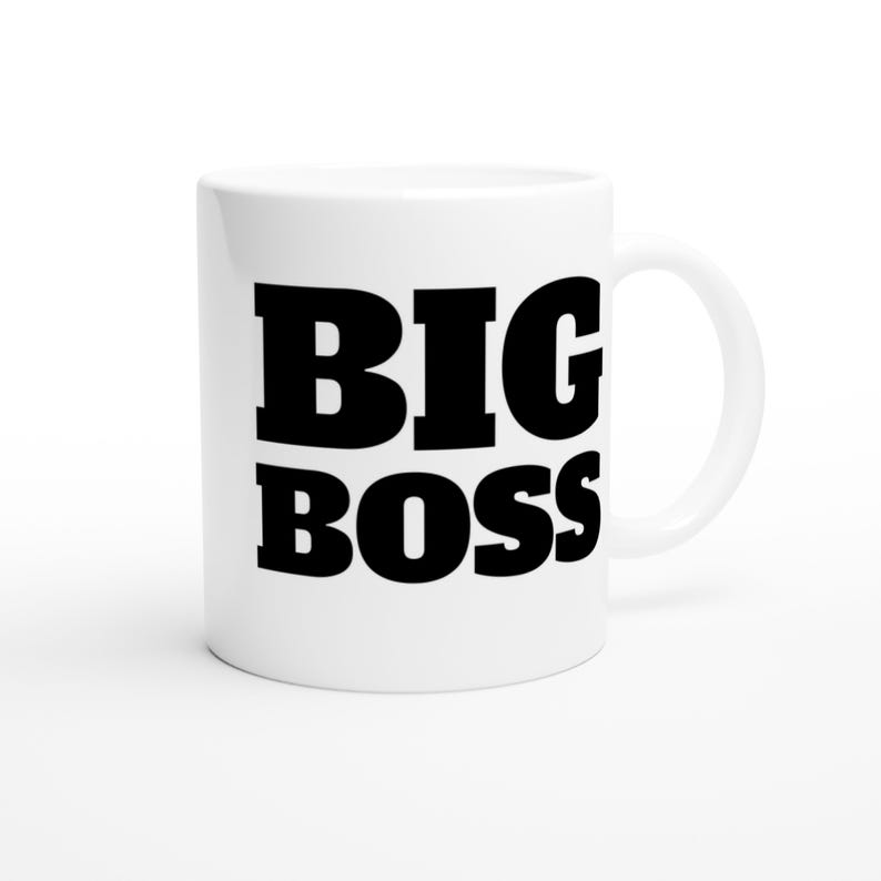 May include: White ceramic mug with the words "BIG BOSS" printed in bold black letters. The mug has a standard handle and a glossy finish. The mug is designed for hot or cold beverages.