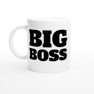 May include: White ceramic mug with the words "BIG BOSS" printed in bold black letters. The mug has a curved handle and is set against a white background. A simple, yet bold design.