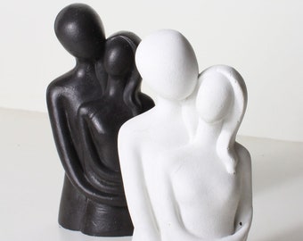 Peut inclure: Deux sculptures abstraites de couples qui s'embrassent, l'une en noir et l'autre en blanc. Les sculptures sont faites d'un matériau lisse et mat et ont un design moderne et minimaliste.