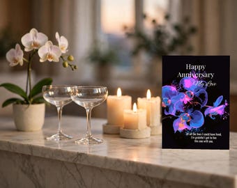 Op de afbeelding: Een rechthoekige wenskaart met een zwarte achtergrond en een illustratie van een blauwe en paarse orchidee. De tekst luidt: Happy Anniversary My Love. Of all the lives I could have lived, I'm grateful I get to live this one with you.