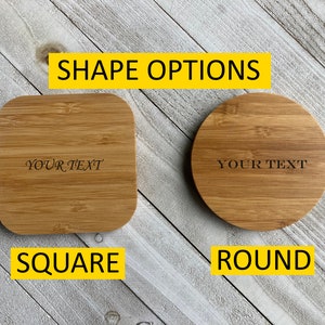 May include: Two wooden coasters, one square and one round, with the text "YOUR TEXT" engraved on each. The coasters are made of natural bamboo and have a light brown color. The coasters are displayed on a white wooden surface.