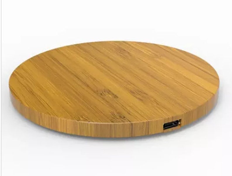 May include: A round, wooden wireless charging pad with a USB-C port on the side. The pad is made of light brown bamboo.