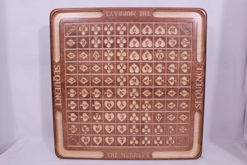 Pu&ograve; includere: Un tabellone da gioco in legno con finitura marrone e marrone chiaro. Il tabellone &egrave; inciso con le parole "SEQUENCE" e "THE MURRAYS". Il tabellone &egrave; diviso in una griglia di quadrati, ognuno dei quali contiene un simbolo di carta da gioco.