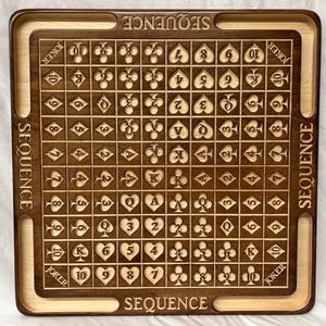 May include: A wooden game board with a grid of 100 squares, each containing a playing card symbol. The board is labeled "SEQUENCE" on all four sides. The board is made of dark brown wood with a light brown border.