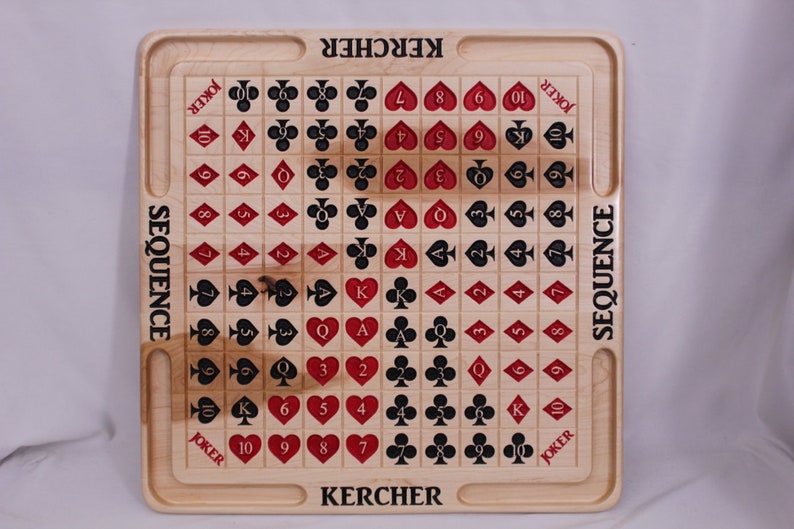 Pu&ograve; includere: Un tabellone da gioco in legno con un design di carte rosse e nere. Il tabellone &egrave; etichettato "SEQUENCE" e "KERCHER".
