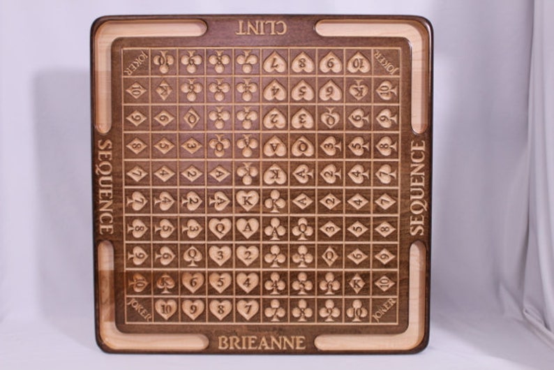 Pu&ograve; includere: Un tabellone da gioco in legno con una griglia di carte, numerate da 2 a 10, Jack, Queen, King e Ace. I semi sono cuori, diamanti, fiori e picche. Il tabellone &egrave; personalizzato con i nomi "Clint" e "Brianne".