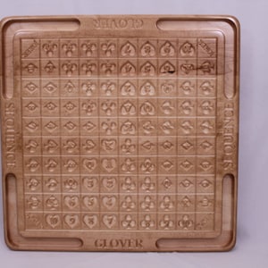 Pu&ograve; includere: Un tabellone da gioco in legno con le parole "SEQUENCE" e "GLOVER" stampate su di esso. Il tabellone &egrave; diviso in una griglia di quadrati, ognuno contenente un simbolo diverso.