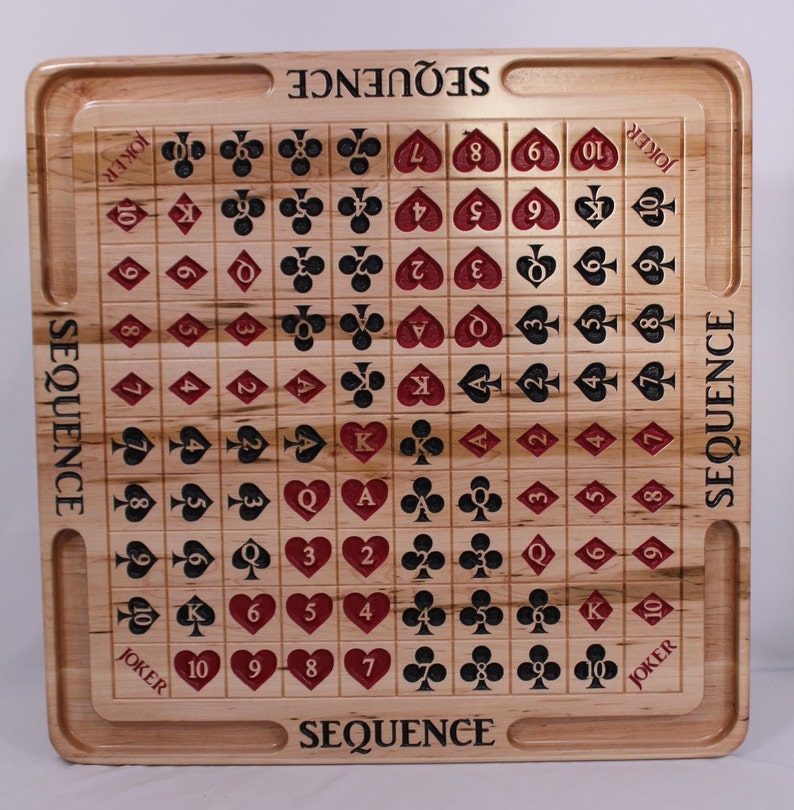 May include: A wooden game board with the word "SEQUENCE" printed on the top and bottom. The board is divided into a grid of squares, each containing a playing card symbol. The cards are arranged in a sequence from Ace to King, with the suits of hearts, diamonds, clubs, and spades.