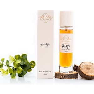 May include: A 30 ml bottle of "Beatific" Eau de Parfum by Goquailca. The bottle is clear glass with a wooden cap and is sitting on a wooden disc. The product is packaged in a white box with gold lettering.
