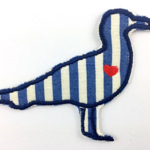 Può includere: Toppa in tessuto a forma di gabbiano, a righe verticali blu e bianche. Il gabbiano ha un cuore rosso sul petto ed è bordato di blu scuro. Ideale per abbigliamento.