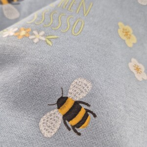 May include: A light blue sweatshirt with embroidered bees and flowers. The text "Love & When" is embroidered in yellow on the front of the sweatshirt.