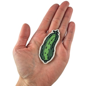 Könnte beinhalten: Ein grüner gestickter Bügeleisen-Aufnäher in Form einer Gurke.