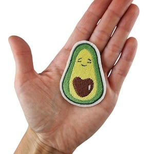 May include: An embroidered avocado patch in green and yellow with a brown heart and a smiling face.