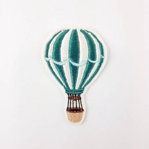 Pode incluir: Patch bordado com um design de balão de ar quente listrado em turquesa e branco. O balão tem uma cesta detalhada e uma borda branca. Este patch é adequado para decorar roupas, bolsas ou outros itens de tecido.