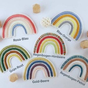 Può includere: Dieci toppe arcobaleno ricamate con diverse combinazioni di colori. Le toppe sono etichettate con le combinazioni di colori: Rosa-Blau, Grün-Rost, Blau-Orange, Regenbogen-Himbeere, Gold-Beere e Regenbogen-Petrol.
