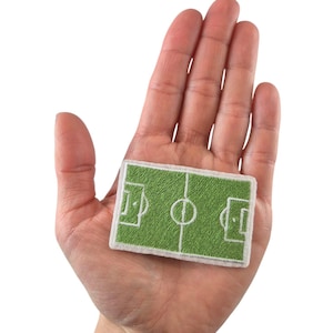 May include: A green and white embroidered patch depicting a soccer field with a center circle and two goals.