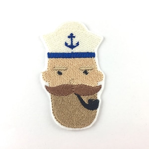 May include: Embroidered patch of a cartoon sailor with a white hat, blue anchor, brown mustache, and a pipe. The sailor has a brown beard and a brown face.