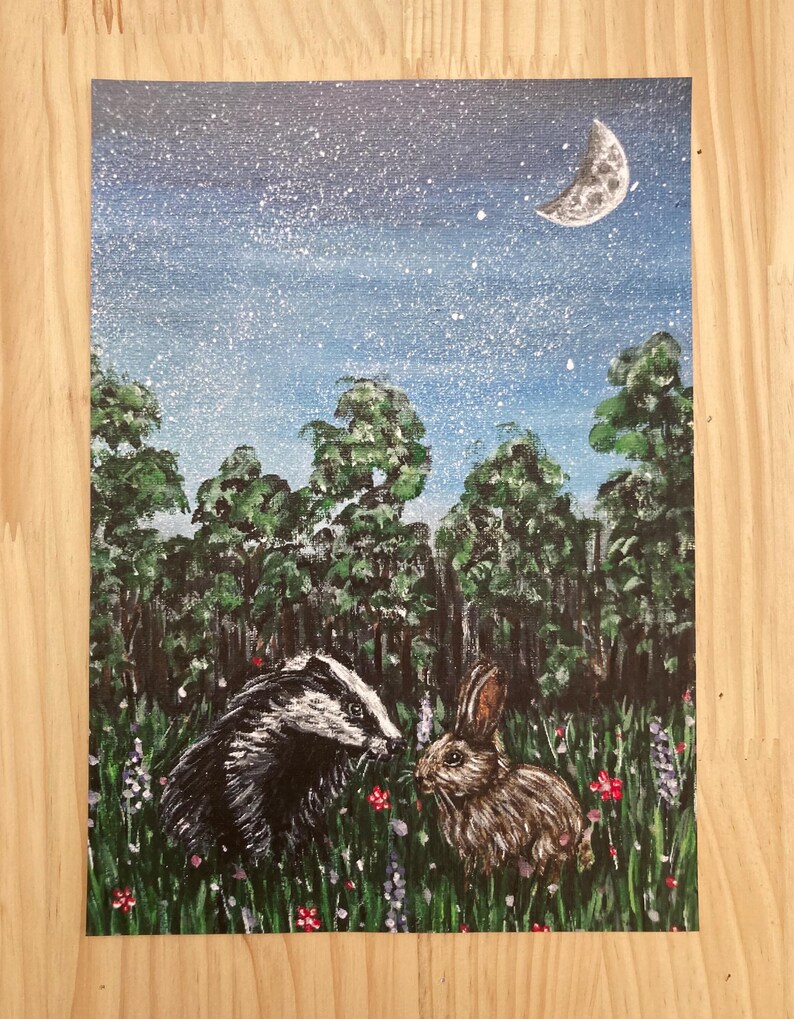 May include: A rectangular painting on canvas featuring a black and white badger and a brown rabbit standing in a green meadow filled with small red and purple flowers. The background shows a dark forest under a starry night sky with a crescent moon.