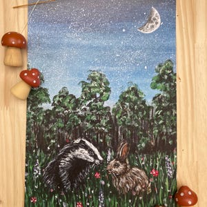 May include: A rectangular art print featuring a painted scene of a badger and a rabbit in a grassy meadow at night. The background shows a dark blue starry sky with a crescent moon above a dense forest of green trees and colorful wildflowers.