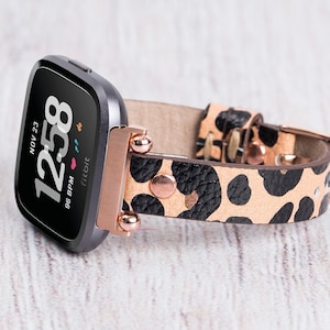 May include: A black and rose gold smartwatch with a leopard print leather strap. The watch face shows the time, date, and heart rate.