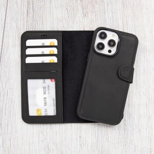 Op de afbeelding: Zwart leren telefoonhoesje met een portemonnee-flap. Het hoesje heeft slots voor creditcards en een vak voor contant geld. Het telefoonhoesje is gesloten en de camera lenzen zijn zichtbaar.