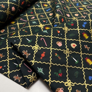 Pode incluir: Tecido verde escuro com um padrão de Natal repetido. O design apresenta linhas de grade douradas com laços e quadrados preenchidos com bonecos de gengibre, bengalas doces, sinos e outros ícones festivos. O tecido está dobrado, mostrando sua textura.
