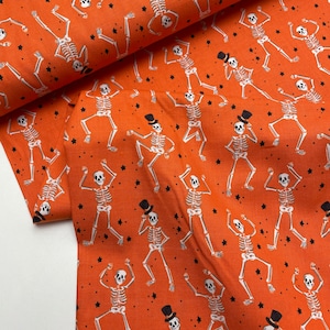 May include: Orange fabric with a repeating pattern of white skeletons dancing. The skeletons are wearing top hats and have a whimsical, cartoon-like appearance.