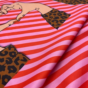 Könnte beinhalten: Gefalteter Stoff mit einem sich wiederholenden Muster aus roten und rosa horizontalen Streifen. Der Stoff hat auch ein Leopardenmuster und eine Grafik von zwei Händen, die ein Herz bilden.
