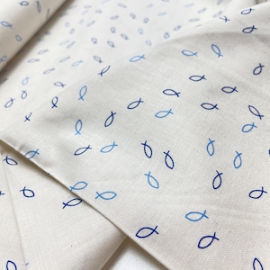 Könnte beinhalten: Weißer Stoff mit einem sich wiederholenden Muster aus blauen Fischsymbolen.