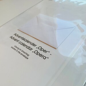 May include: A white envelope with the text "Adventskalender "Oper" - Advent calendar "Opera" L&ouml;sung im Umschlag solution in the envelope" printed on it.