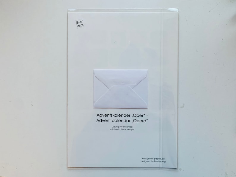 May include: A white envelope with a white card inside. The card has the text "Adventskalender "Oper" - Advent calendar "Opera"  L&ouml;sung im Umschlag solution in the envelope" and the website address "www.yellow-popen.de" and the text "designed by Iva Ludwig".