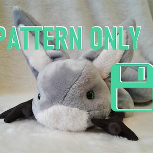 Könnte beinhalten: Ein Plüschtier in Form einer stilisierten Fledermaus, hauptsächlich grau mit weißen Akzenten und schwarzen Flügeln. Der Text "PATTERN ONLY" ist grün dargestellt. Ein grünes Disketten-Symbol ist ebenfalls vorhanden.