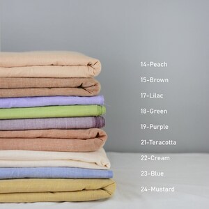 May include: A stack of 10 fabric swatches in various colours, including peach, brown, lilac, green, purple, terracotta, cream, blue, and mustard. The swatches are folded and stacked on top of each other.