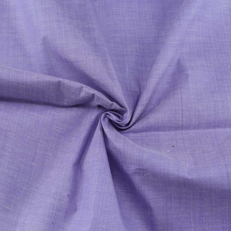 Pu&ograve; includere: Un primo piano di un tessuto morbido, liscio e di colore lilla chiaro con una texture sottile. Il tessuto &egrave; piegato e drappeggiato, mostrando il suo drappeggio e la sua texture.