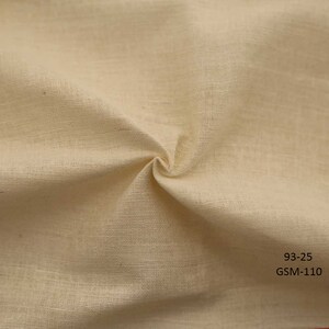 May include: Close-up of a natural off-white fabric with a slightly textured surface. The fabric is folded and draped, showing its soft and drapey quality. The text "93-25 GSM-110" is printed in black at the bottom right corner of the image.