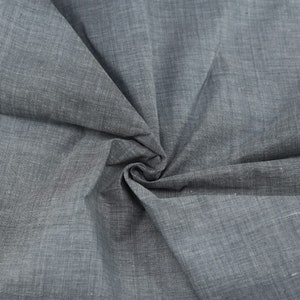 Op de afbeelding: Een close-up van een grijze stof met een textuurweefsel. De stof is gevouwen en gekreukt, waardoor de textuur en de drape zichtbaar worden.